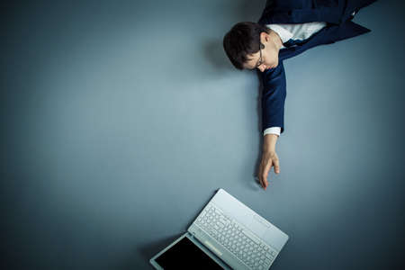 Mature businessman stretches to laptopの写真素材