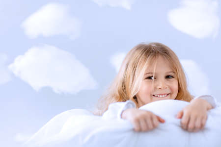 Little smiling girl in bedの写真素材