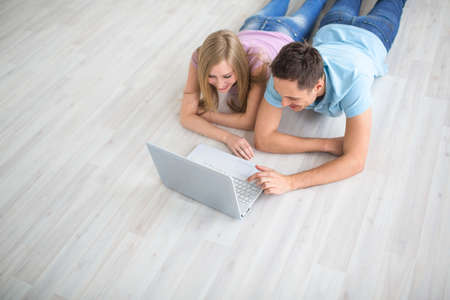 Smiling couple with a laptop on the floor