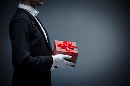 Young man in a tuxedo with a giftsの写真素材