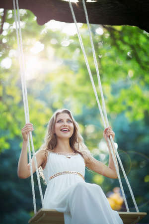 Smiling young woman on a swingの写真素材