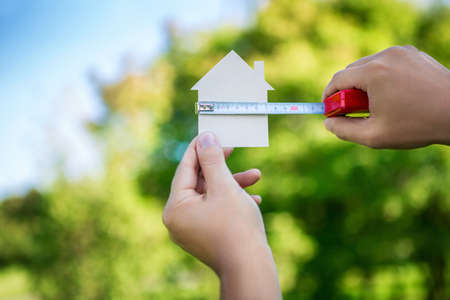 Man's hand measures the cardboard houseの写真素材