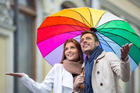 Happy couple with an umbrella on the streetの写真素材