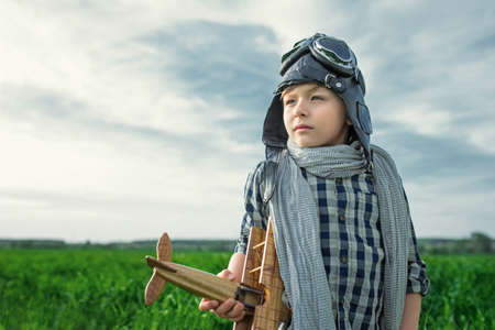 Little boy with wooden airplane in the field