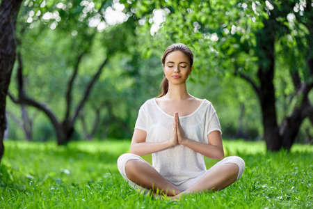 Young girl in lotus pose outdoorsの写真素材