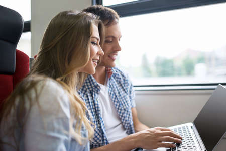 Young couple with a laptop on the trainの写真素材