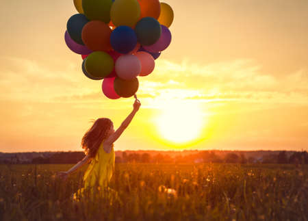 Little girl with balloons on the Sunsetの写真素材