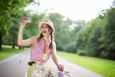 Beautiful girl on a bicycle makes selfieの写真素材