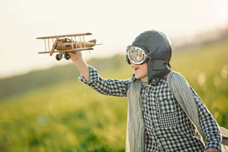Little boy with wooden airplane in the fieldの写真素材
