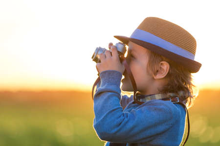 Smiling boy with a camera in the fieldの写真素材