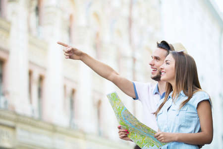 Smiling couple with a map on the streetの写真素材