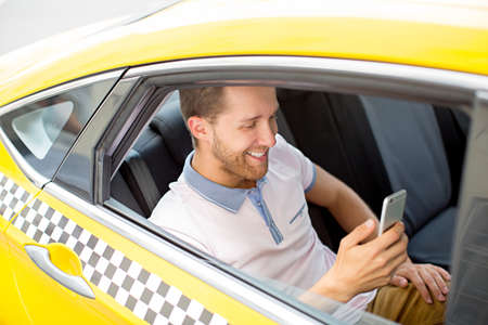 Young man with phone in a taxiの写真素材