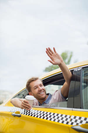 Young man with coffee in a taxiの写真素材