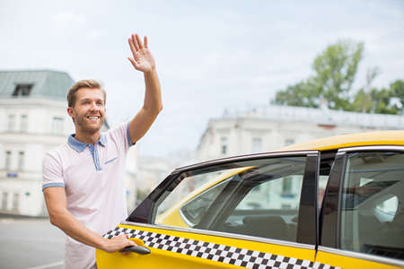 Happy young man with taxiの写真素材