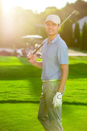 Young golfer with club on a lawnの写真素材