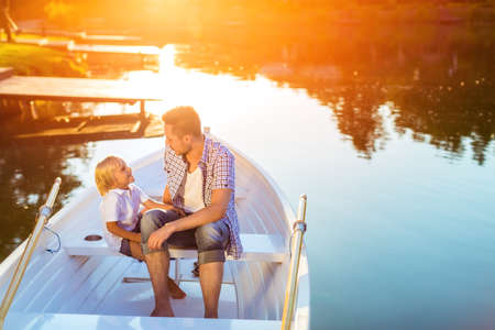 Dad and son in boat at sunsetの写真素材
