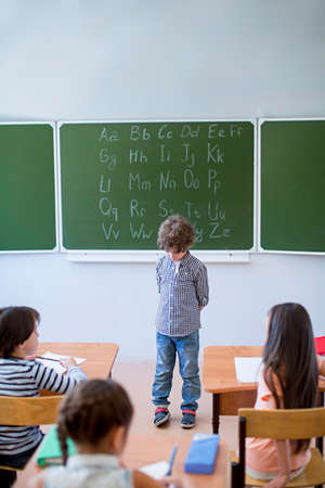 Little schoolgirl with book at blackboard