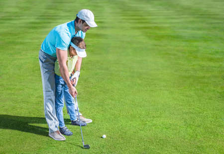 Dad and son playing golfの写真素材