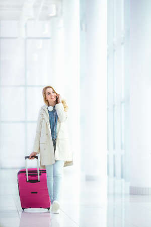Smiling girl with suitcase in airportの写真素材