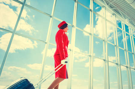 Young stewardess with a suitcase at airportの写真素材