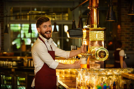 Smiling bartender pours a beer indoorsの写真素材