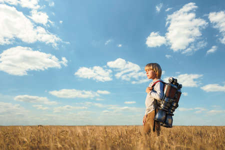 Little boy with a backpack in wheat fieldの写真素材