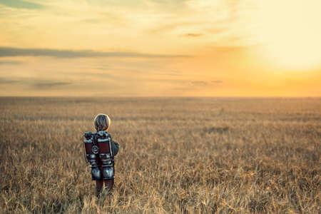 Little boy with a backpack in a fieldの写真素材