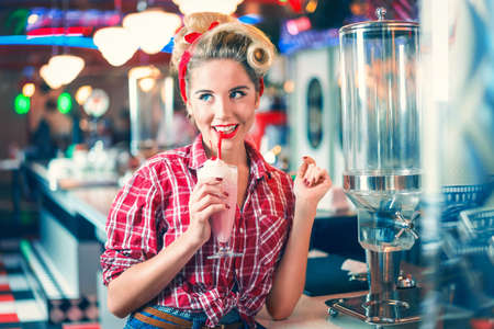 Young girl drinking milkshake in cafeの写真素材