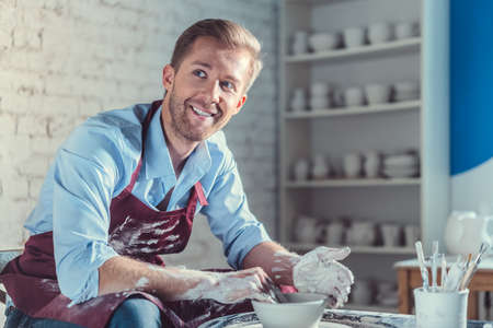 Smiling man in apron in pottery