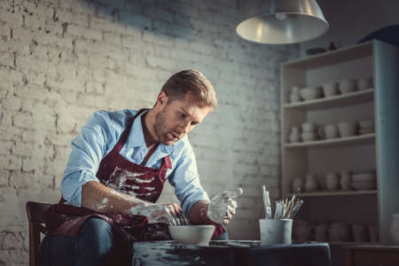 Young man in apron in potteryの写真素材