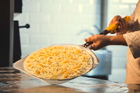Cook preparing pizza in kitchenの写真素材