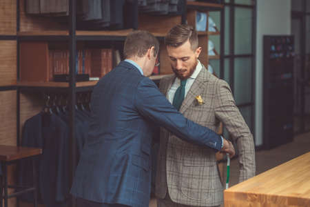 Tailor measures a man in studioの写真素材