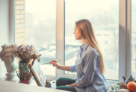 Young girl drawing at the windowの写真素材