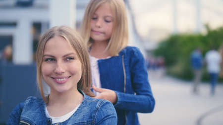 Girl doing her mother's hair outdoors