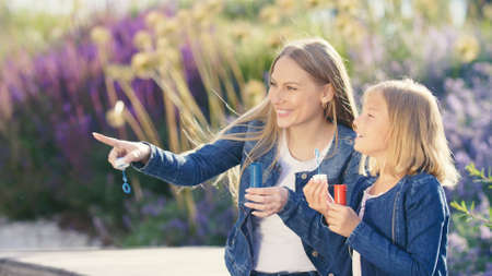 Happy mother and daughter with soap bubbles in the parkの写真素材