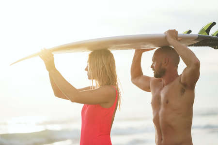 Young couple with surfboard in the sunlightの写真素材
