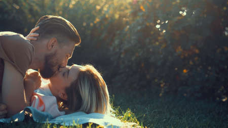 Kissing young couple on the lawn outdoorsの写真素材