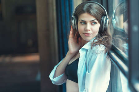 Young girl listening to music on headphones indoorsの写真素材