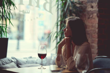 Young attractive girl with a glass of red wine indoorsの写真素材