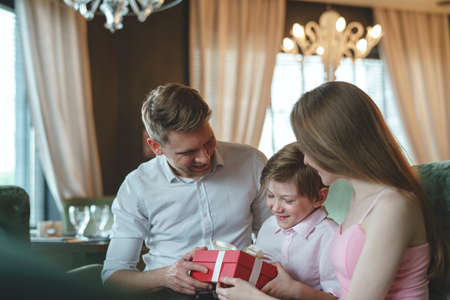 Smiling family with a gift in a restaurantの写真素材