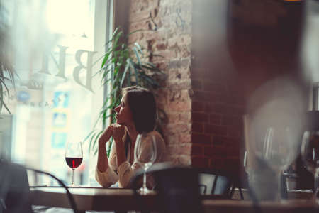 Attractive girl with a glass of red wine indoorsの写真素材