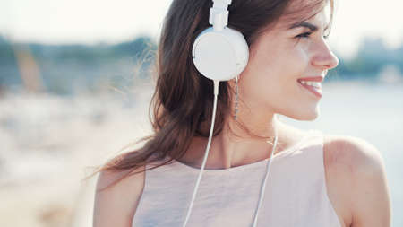 Smiling young girl listen to music with headphones outdoorsの写真素材