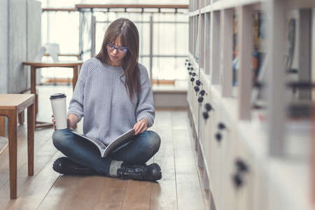 Young woman reading a book in the libraryの写真素材