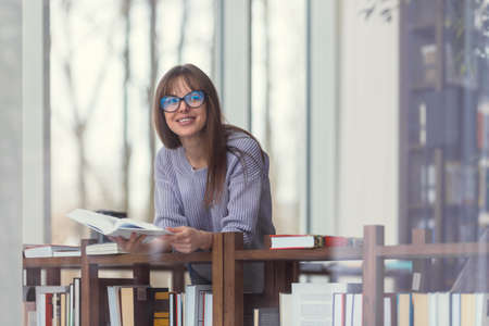 Smiling girl with books in a bookstore