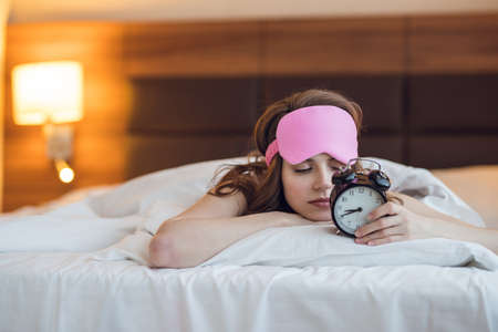Sleeping young girl with an alarm clock indoorsの写真素材