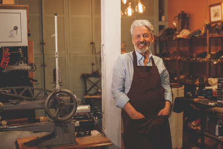Smiling elderly shoemaker in uniform