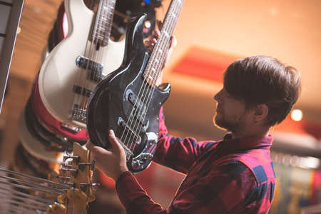 Young man choosing a bass guitarの写真素材