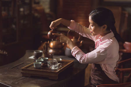 Young tea master pouring tea indoorsの写真素材