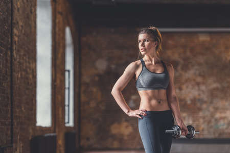 Young athletic girl with dumbbells in the loftの写真素材