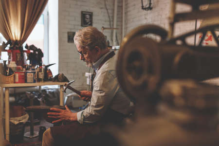 An elderly shoemaker at workの写真素材